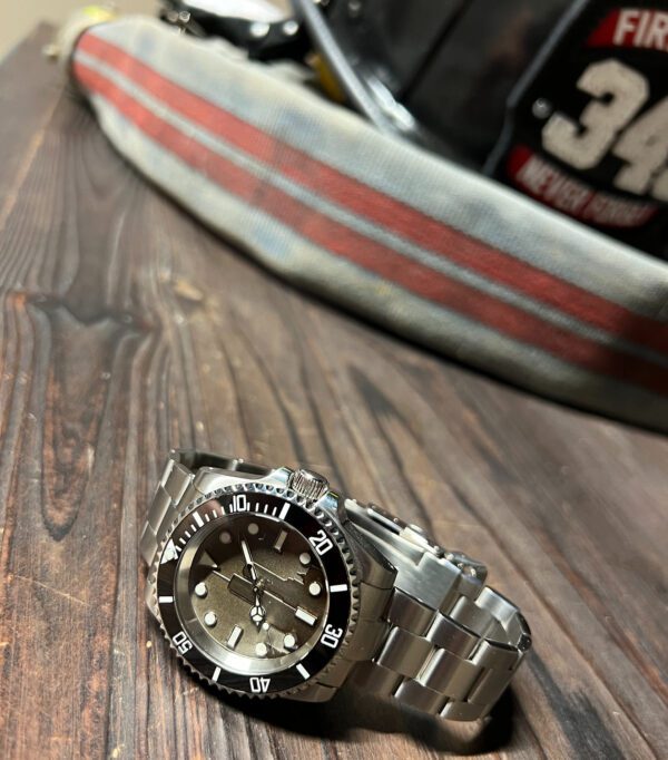 Stainless Steel watch displayed next to an FDNY Firefighter helmet labeled 343