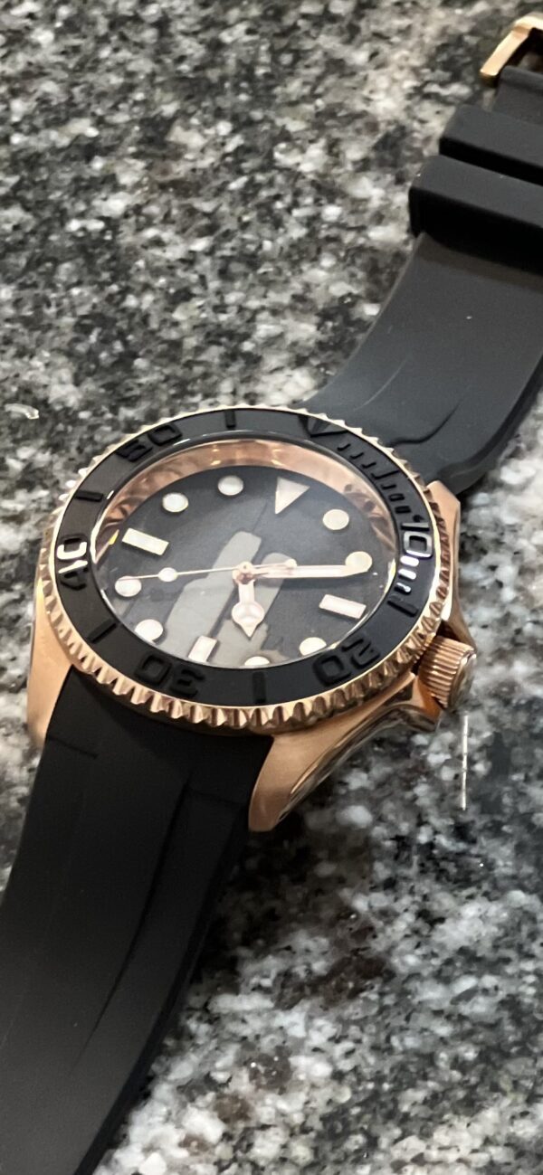 A Rose Gold watch laying on a granite countertop